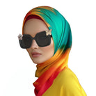 Middle Eastern woman wearing a hijab and a pair of black sunglasses with two charms: a light pink sakura flower with gems on the left and a golden butterfly on the right.